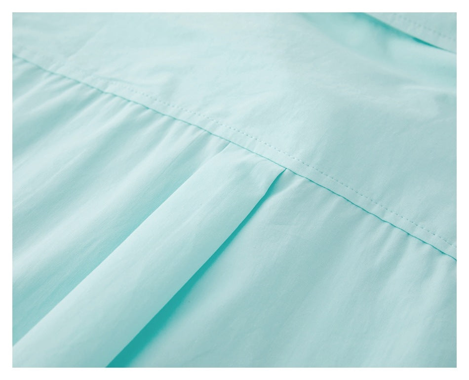 Close-up of pale aqua garment fabric with a stitched seam and folded pleat.