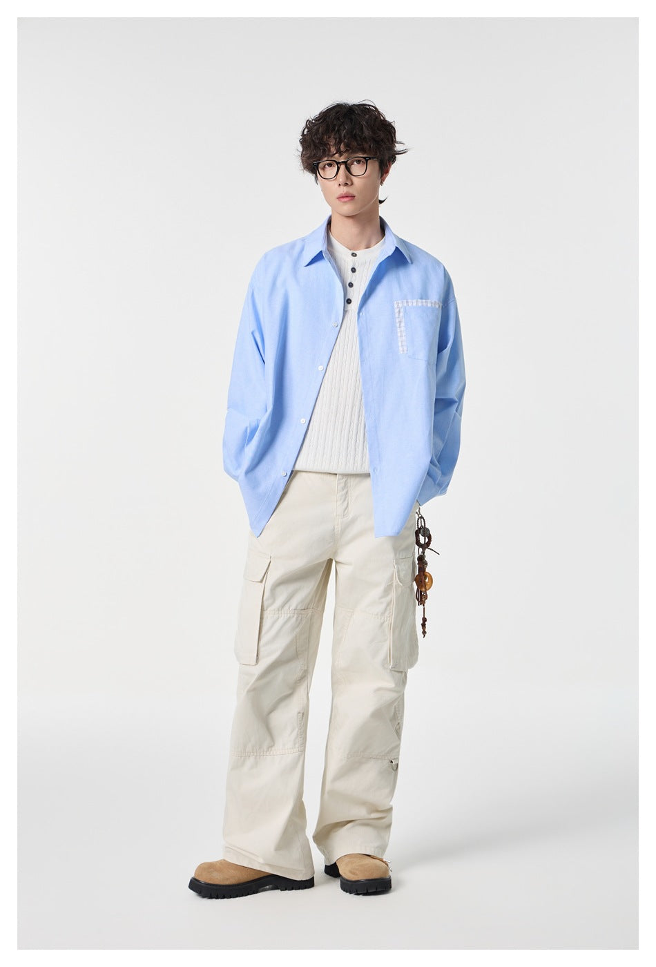 Full-length front view of a model wearing a light blue button-up shirt and cream cargo pants.