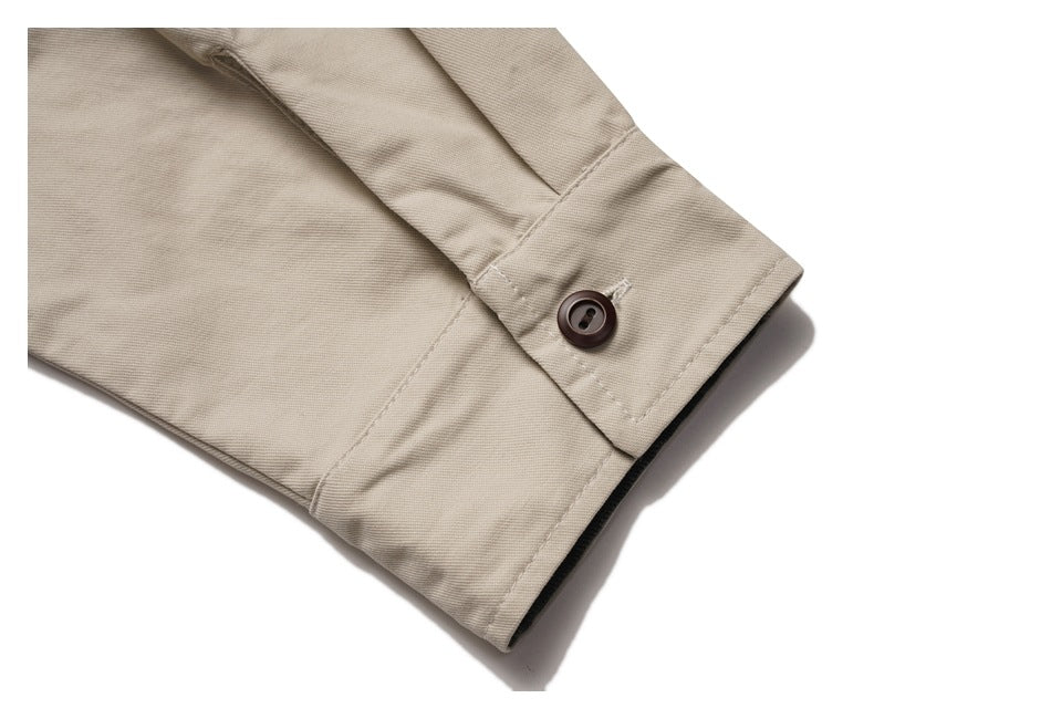 Close-up of the beige jacket sleeve cuff with a dark button and stitched placket.