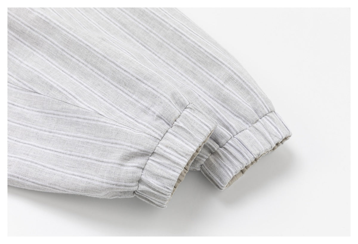 Close-up of light gray striped fabric with gathered elastic sleeve cuffs.