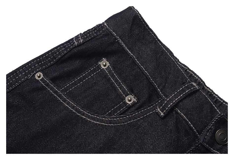 Close-up of the small front coin pocket and rivets on black denim jeans with contrast stitching.