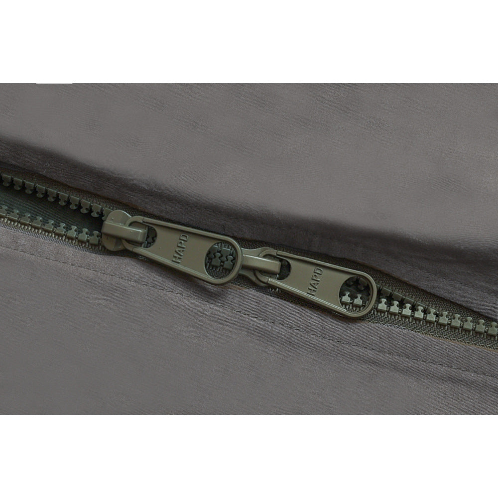 Macro view of a dark olive double zipper on gray jacket fabric.
