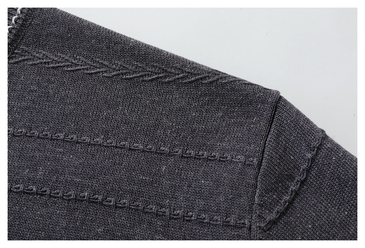 Close-up of a charcoal sweater shoulder showing braided and looped horizontal knit details.