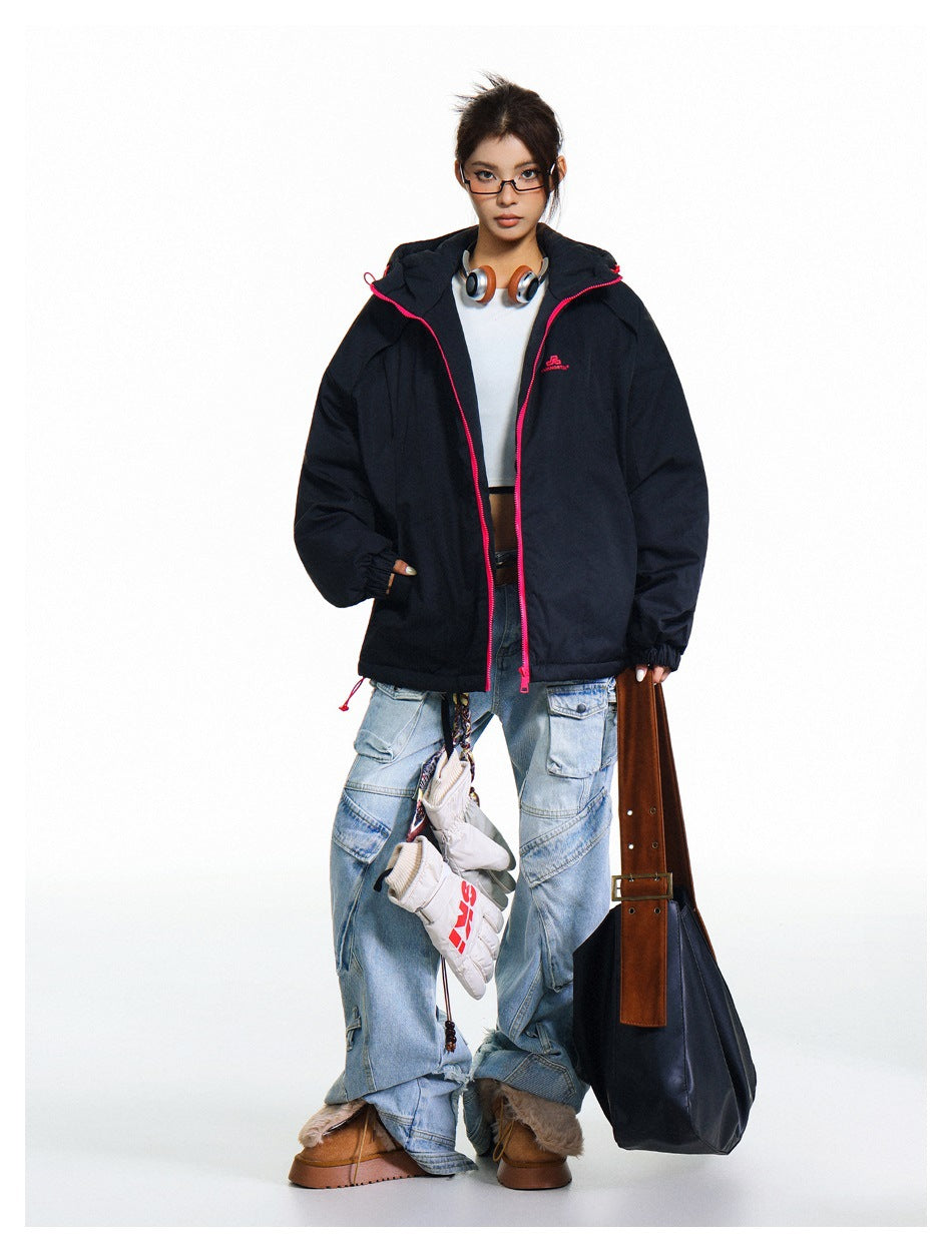 Model wearing an open black hooded jacket with bright pink trim over a white cropped top and light blue cargo jeans.