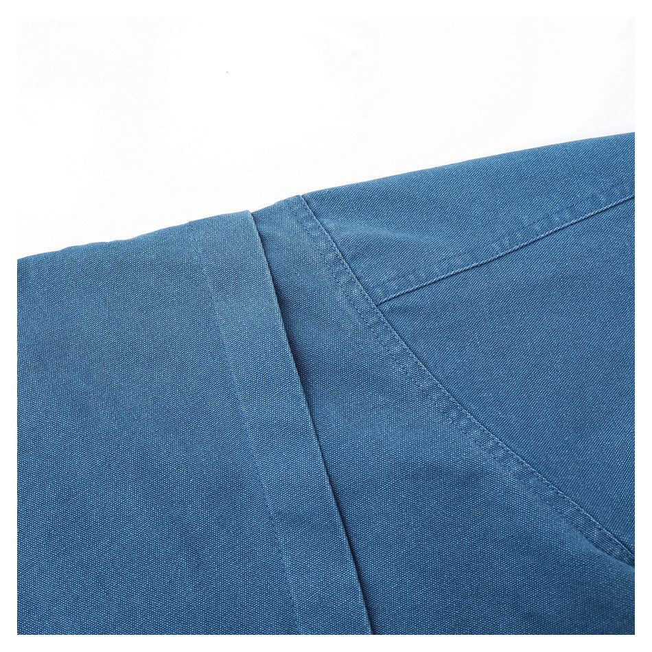 Close-up of blue garment construction with stitched seams and an overlapping fabric panel.