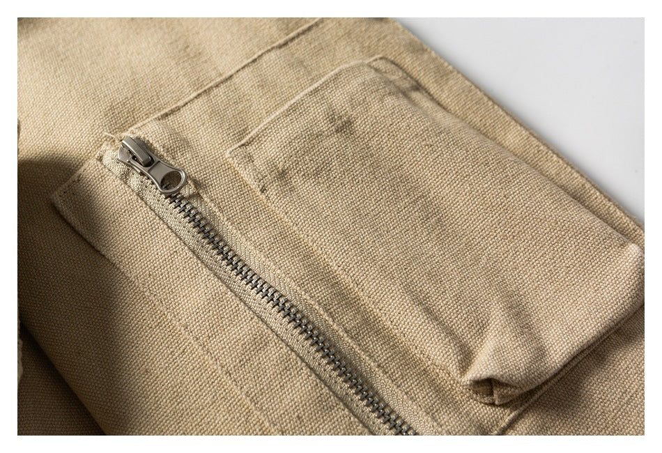 Close-up of a zippered pocket on beige textured garment fabric.