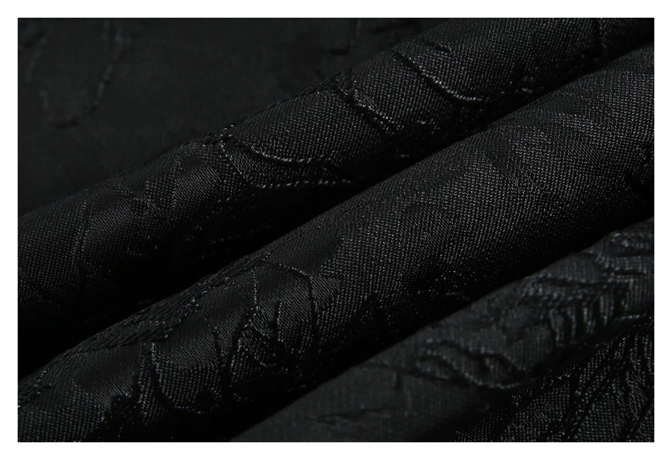 Close-up of folded black fabric showing a subtle tonal floral pattern and textured weave.