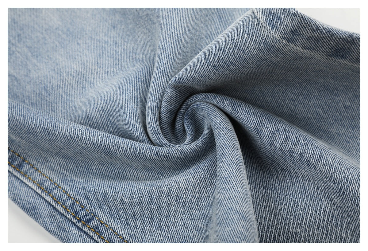 Close-up of light blue denim gathered into a swirl, showing its diagonal weave and texture.