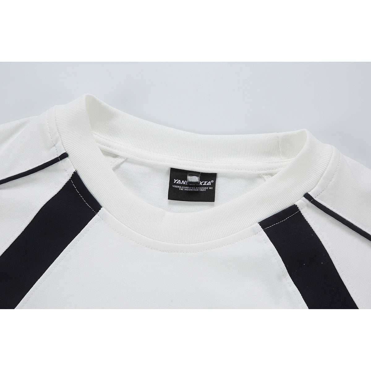 Close-up of a white crewneck shirt collar with dark contrasting shoulder panels and an inside neck label.