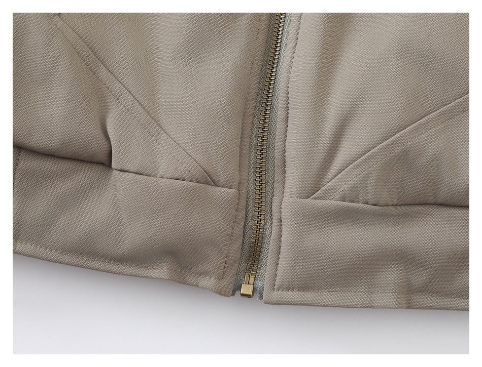 Close-up of the jacket's brass-tone zipper, angled front pockets, and stitched hem.