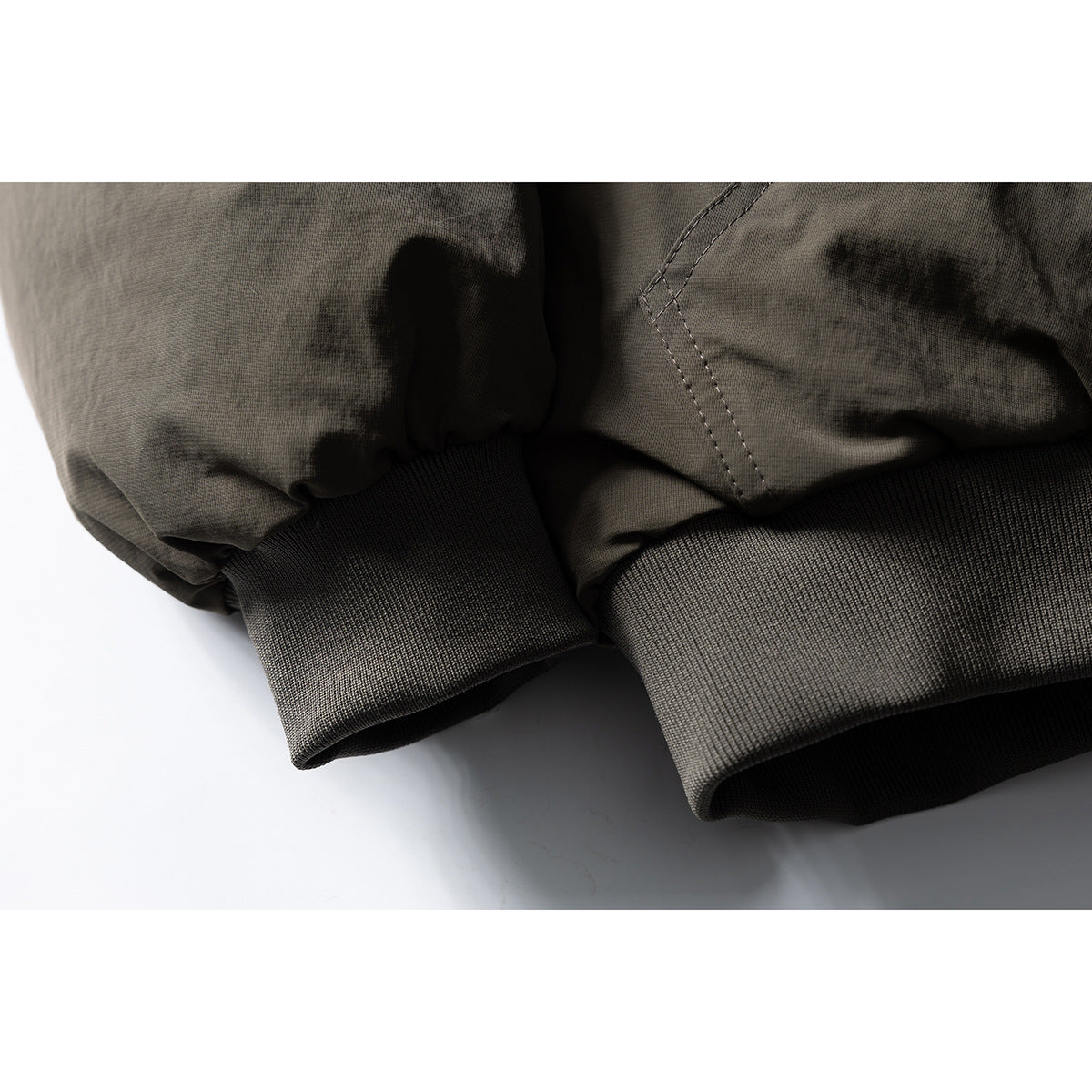 Close-up of an olive-gray jacket sleeve and wide rib-knit cuff.