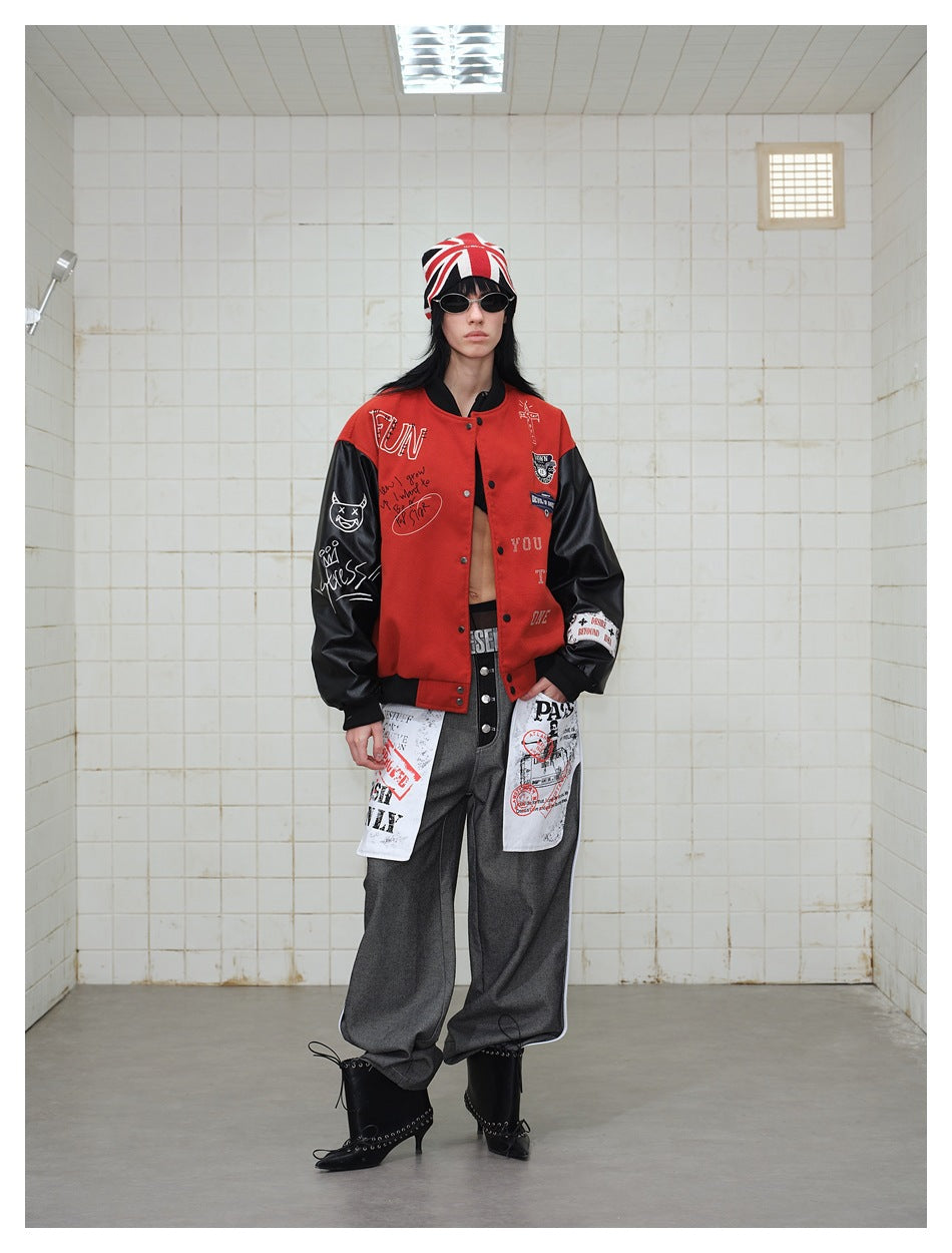 Model wearing a red varsity jacket with black sleeves, graphic patches and lettering, paired with gray trousers and black