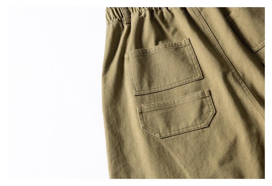 Close-up of two stitched pockets on olive-khaki shorts.