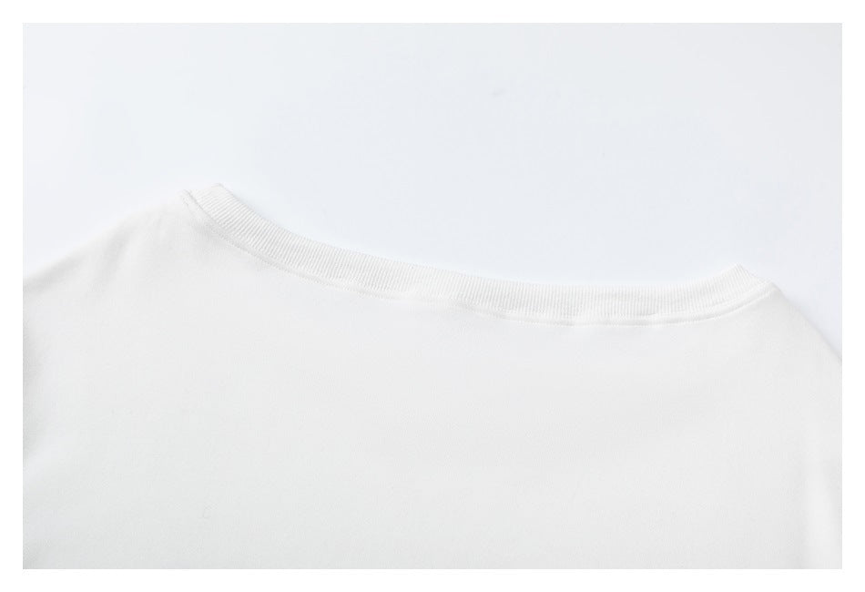 Close-up of the white garment's ribbed crew neckline and shoulder seams.