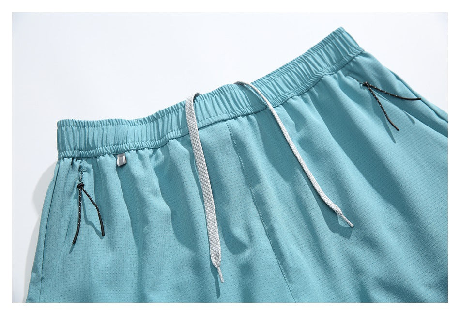 Close-up of light blue shorts showing the elastic waistband, white drawstrings and black zippered pockets.