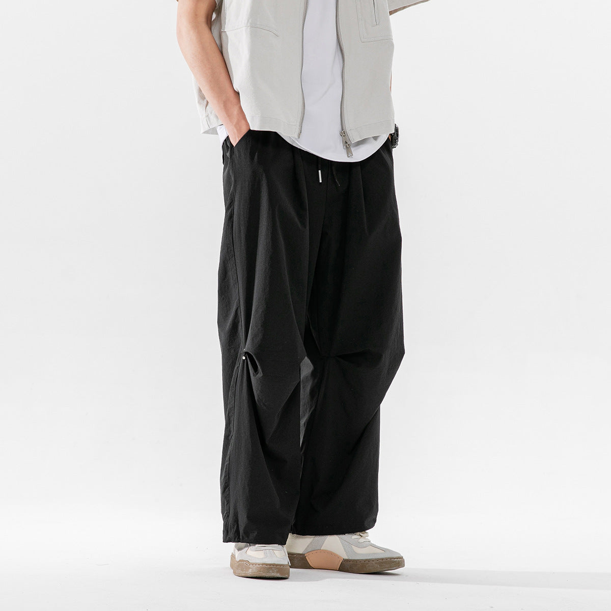 Front view of a model wearing loose black drawstring trousers with wide legs.