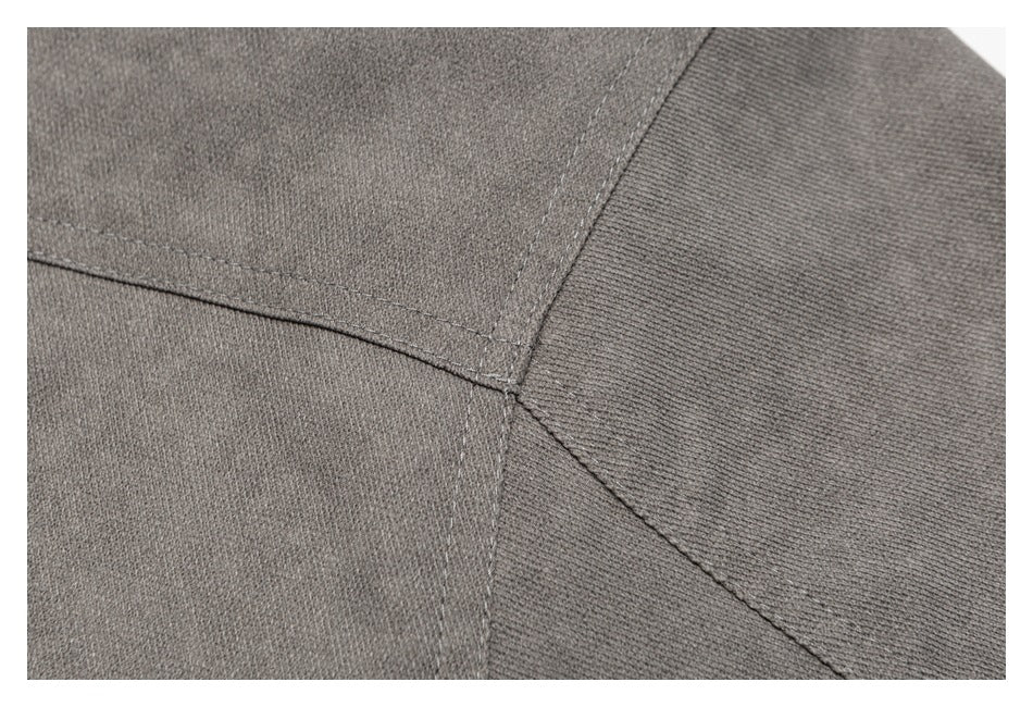 Close-up of intersecting stitched seams on charcoal gray fabric.