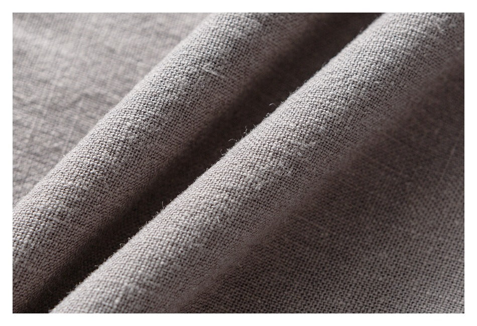 Macro view of the textured woven fabric of light gray trousers, folded into soft ridges.