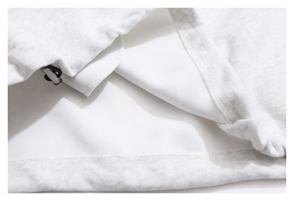 Inside close-up of a light gray heathered garment hem with stitching and a small metal toggle.