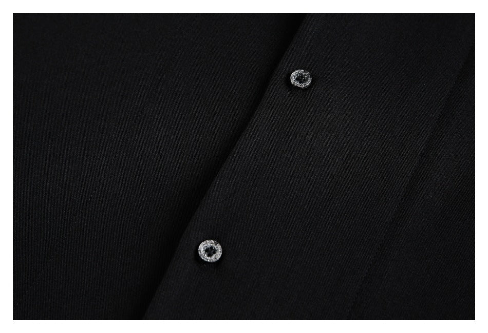 Close-up of a black garment's placket with two round decorative buttons.