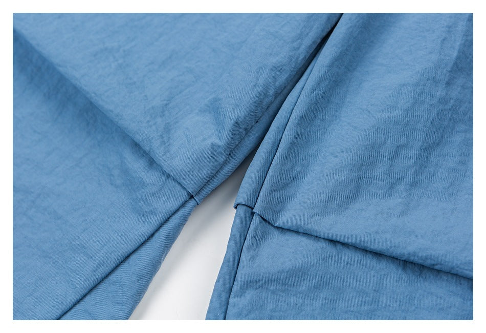 Close-up of blue shorts showing stitched fabric panels and a folded seam.