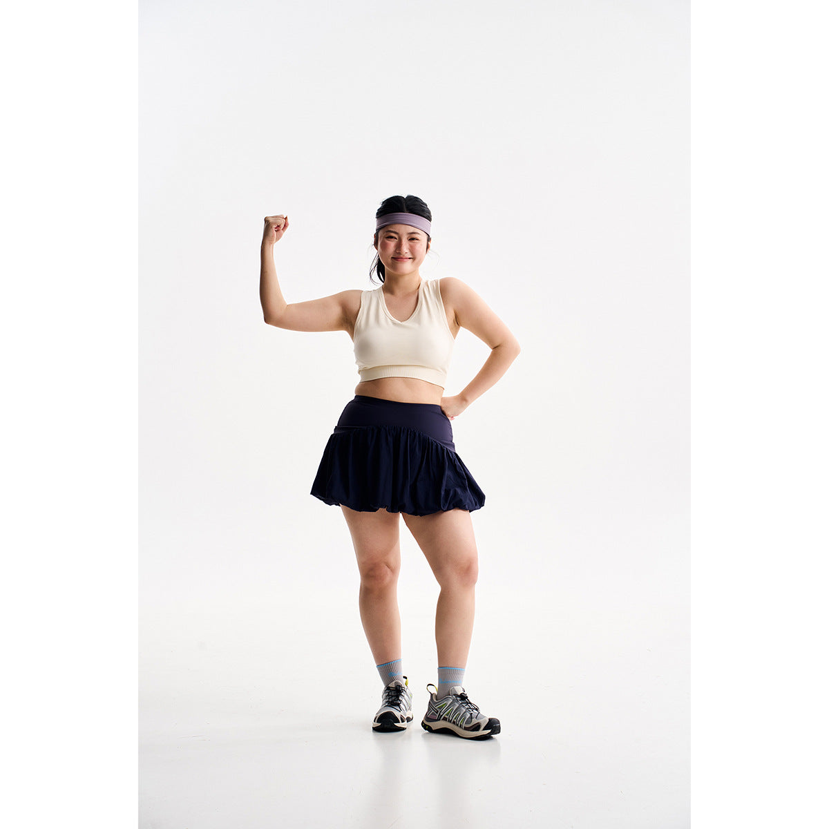 Model wearing a cream cropped tank and dark navy flared skirt with a lavender headband.