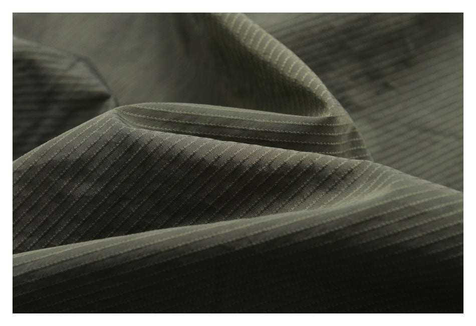Close-up of olive-gray fabric with fine diagonal pinstripes and folded seams.