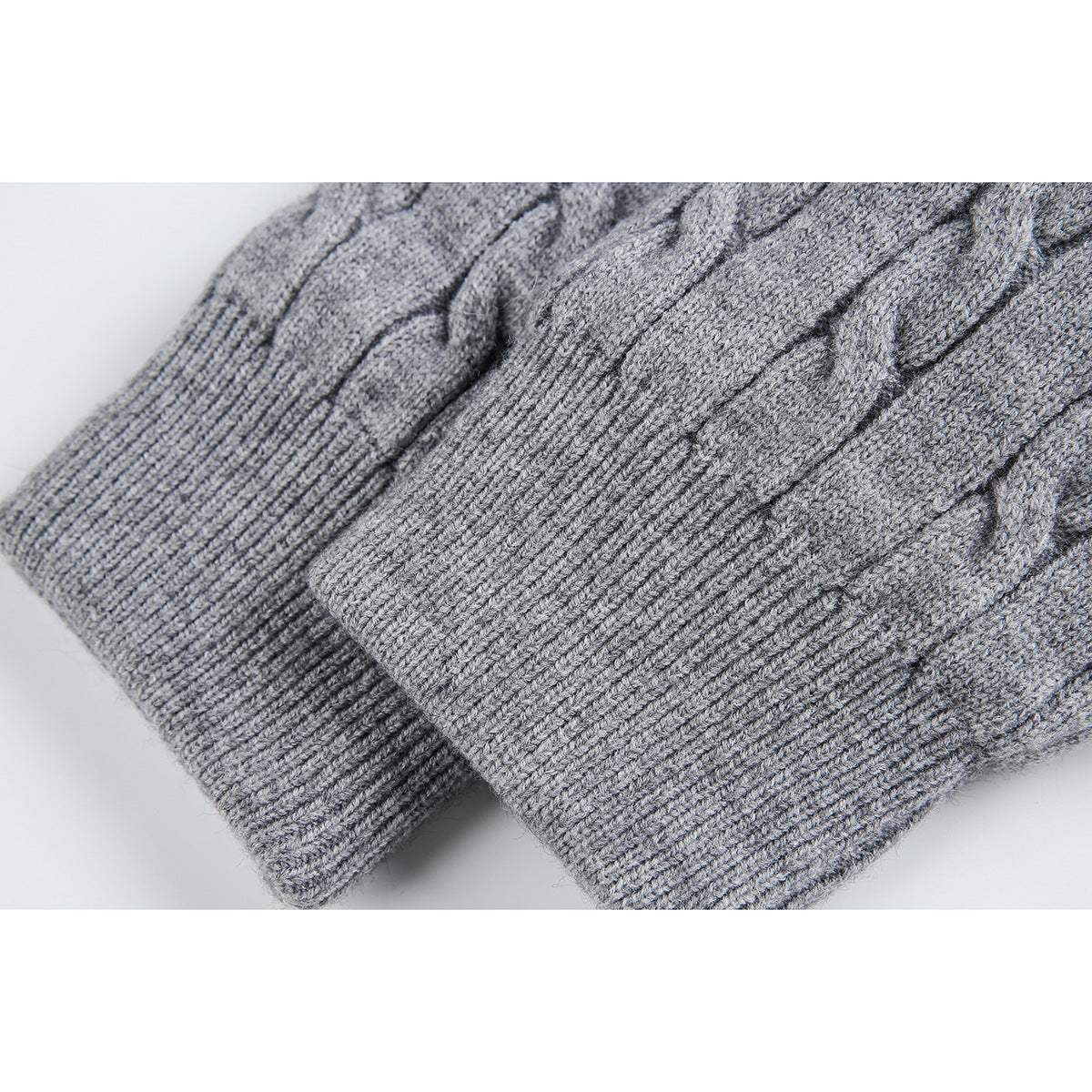 Close-up of a gray cable-knit cardigan sleeve and wide ribbed cuff.