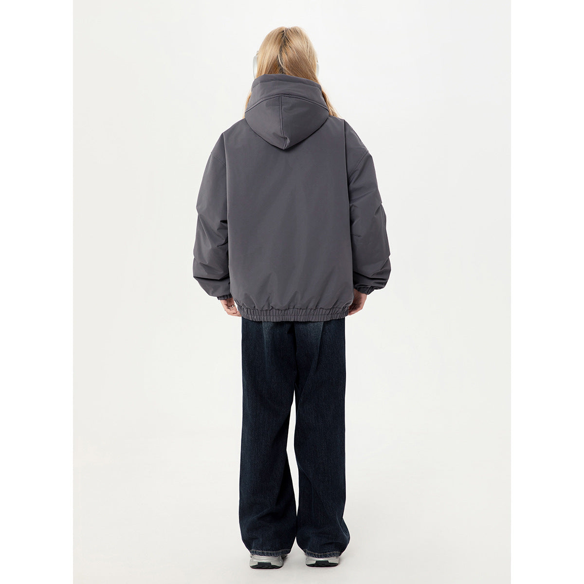 Back view of a model wearing a charcoal gray hooded jacket with an elastic hem.