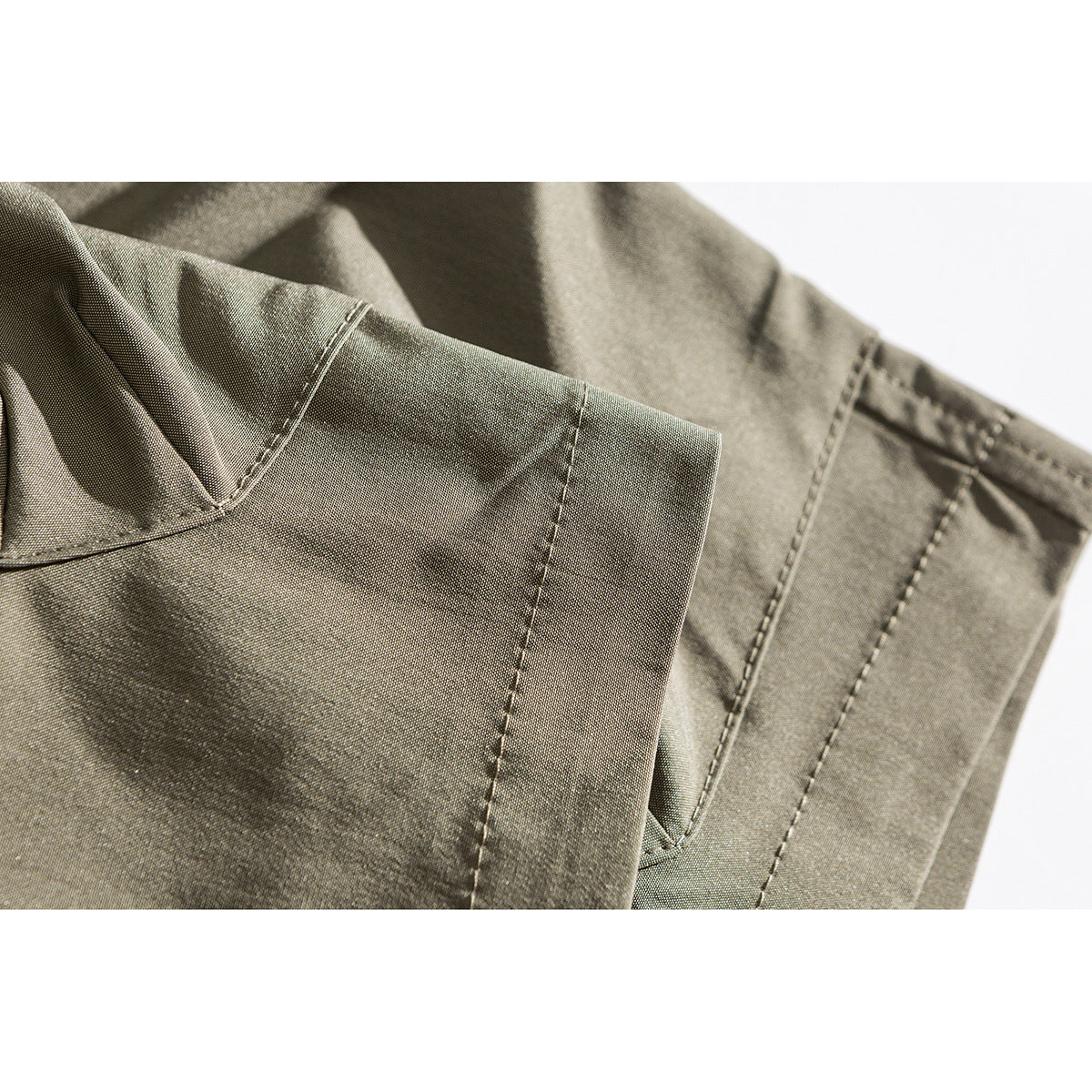 Close-up of khaki shorts fabric and stitched seams around a pocket edge.