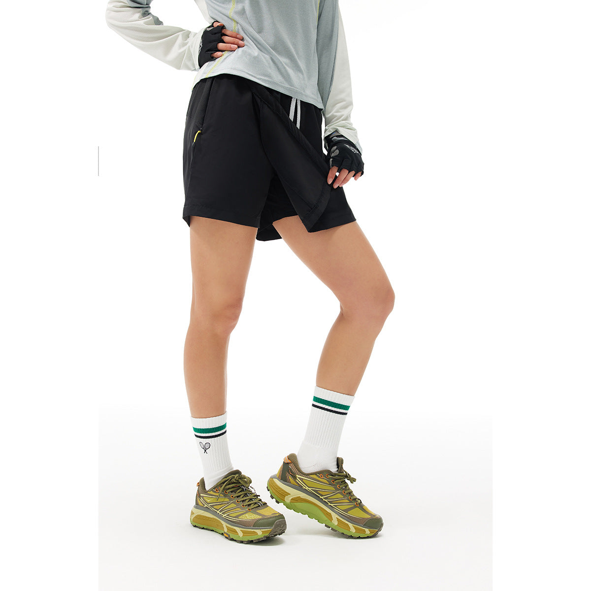 Model wearing black athletic shorts with an overlapping front panel and a zip pocket, shown from the front.
