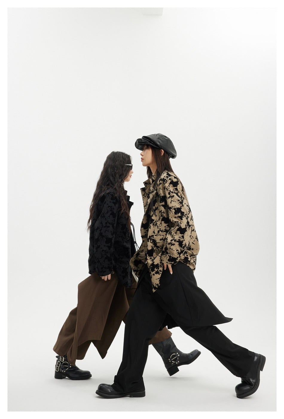 Two models walk past each other in side view wearing the jacket in black and taupe printed colorways.