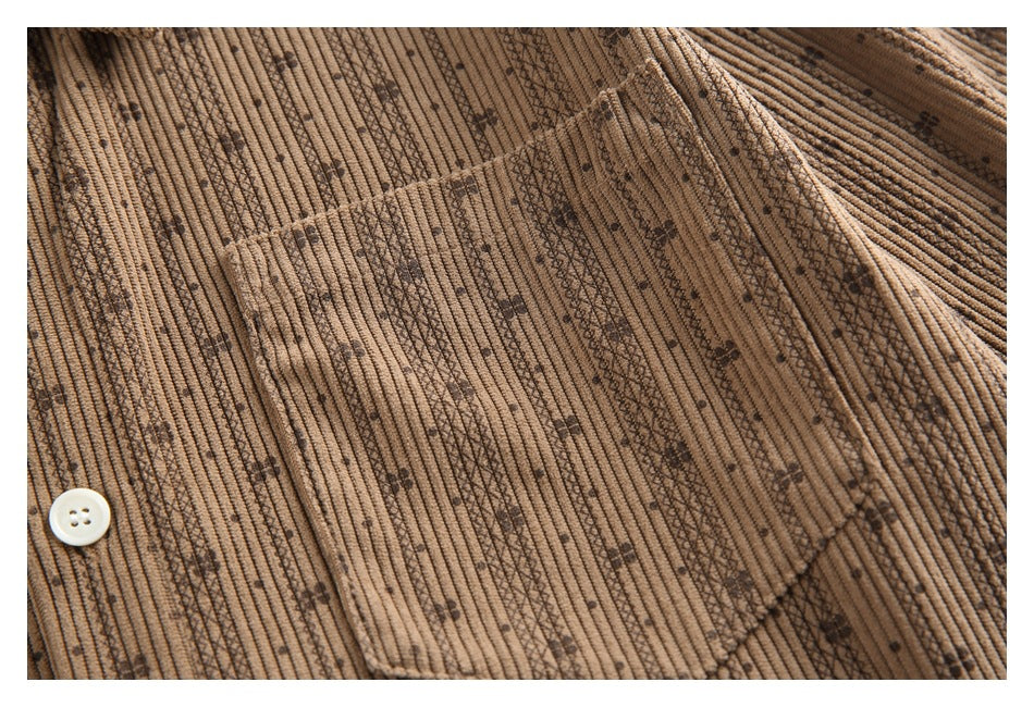 Close-up of the tan shirt's chest pocket and dark patterned vertical stripes, with a white button at the edge.