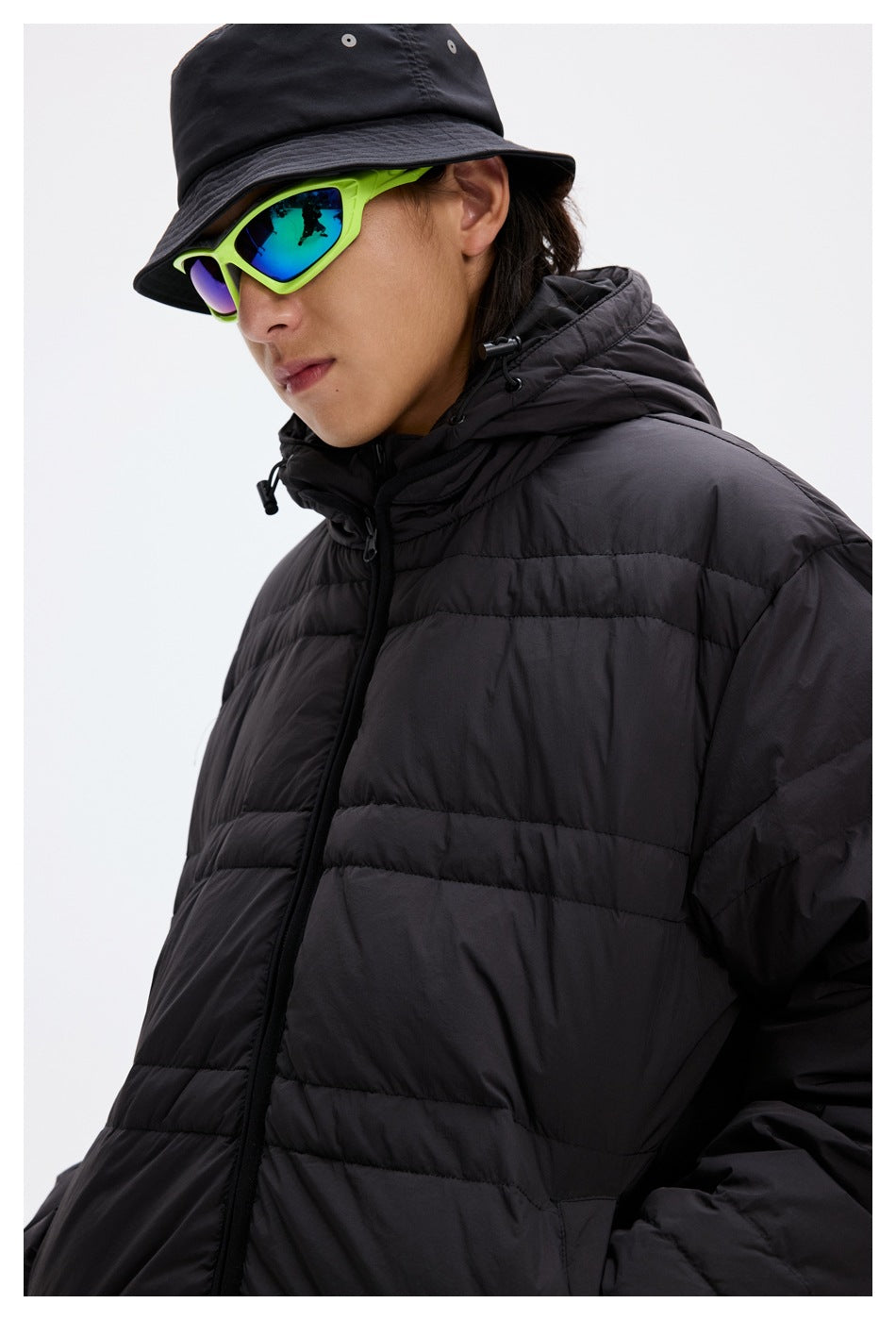 Close-up of a model wearing a black quilted puffer jacket with a raised hood and front zipper.