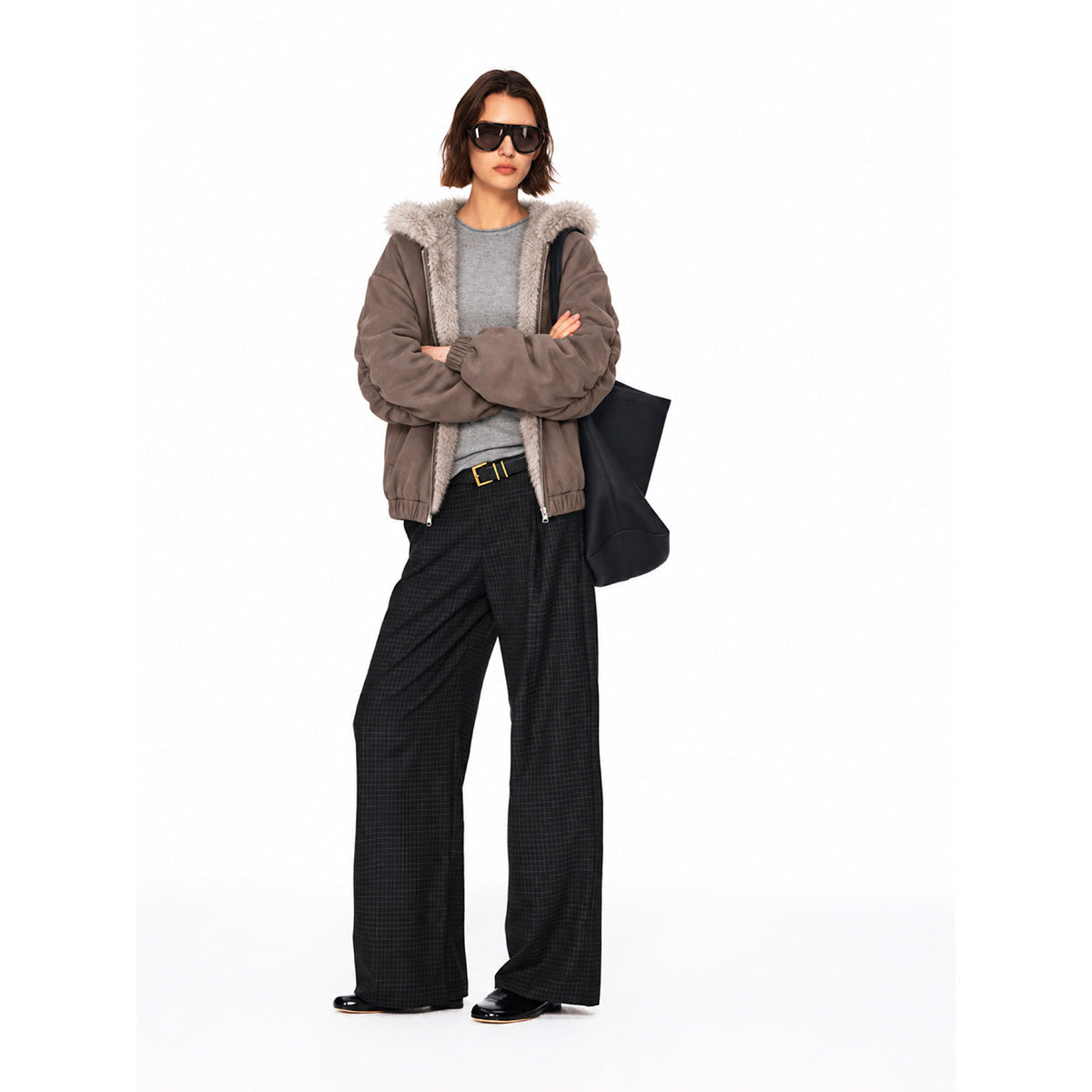 Woman wearing a taupe faux-fur-trimmed hooded jacket with a gray top and wide-leg plaid trousers.