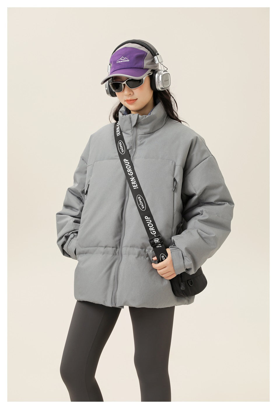 Model wearing a gray high-collar padded jacket with a front zipper and large front pockets.