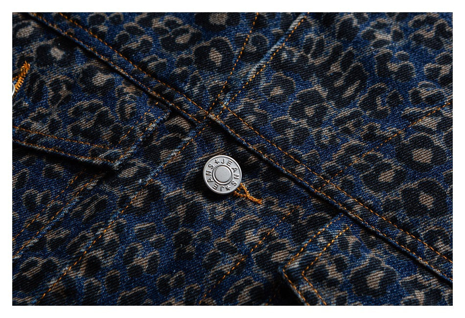 Close-up of a silver button and orange topstitching on blue leopard-print denim.
