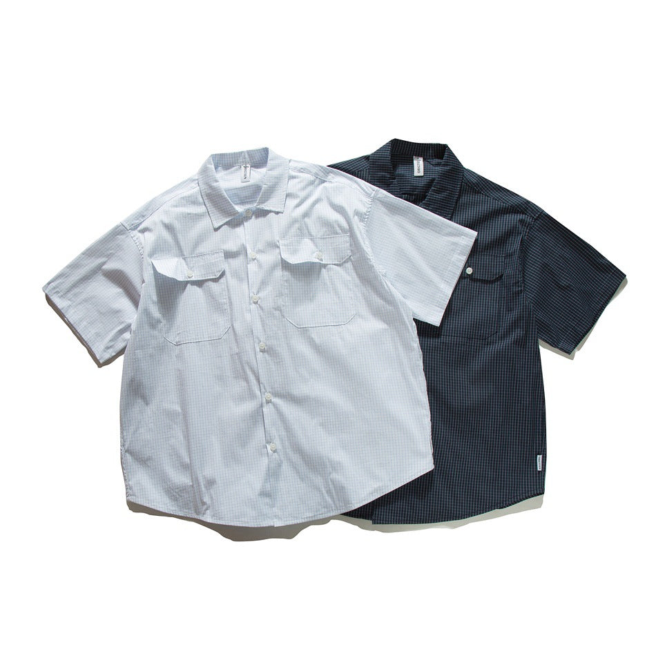 Two short-sleeved button-up shirts with a fine grid pattern, one pale and one dark, shown from the front.