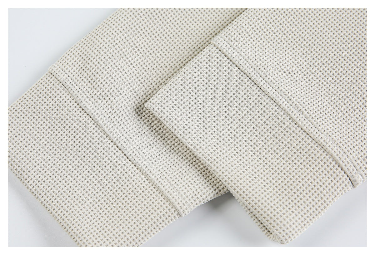 Close-up of an off-white sleeve cuff and adjacent seam in textured fabric.
