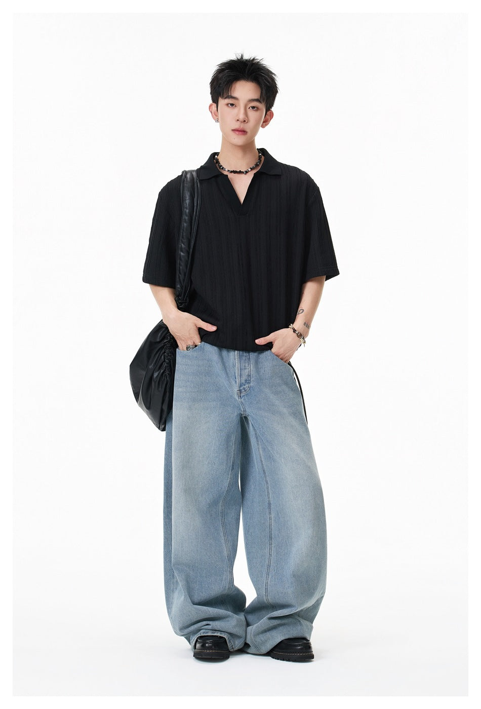 Full-length model wearing a black textured short-sleeve polo with wide light-blue jeans.