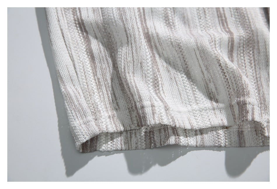 Close-up of the finished bottom hem and vertical openwork stripes on an ivory knit polo shirt.