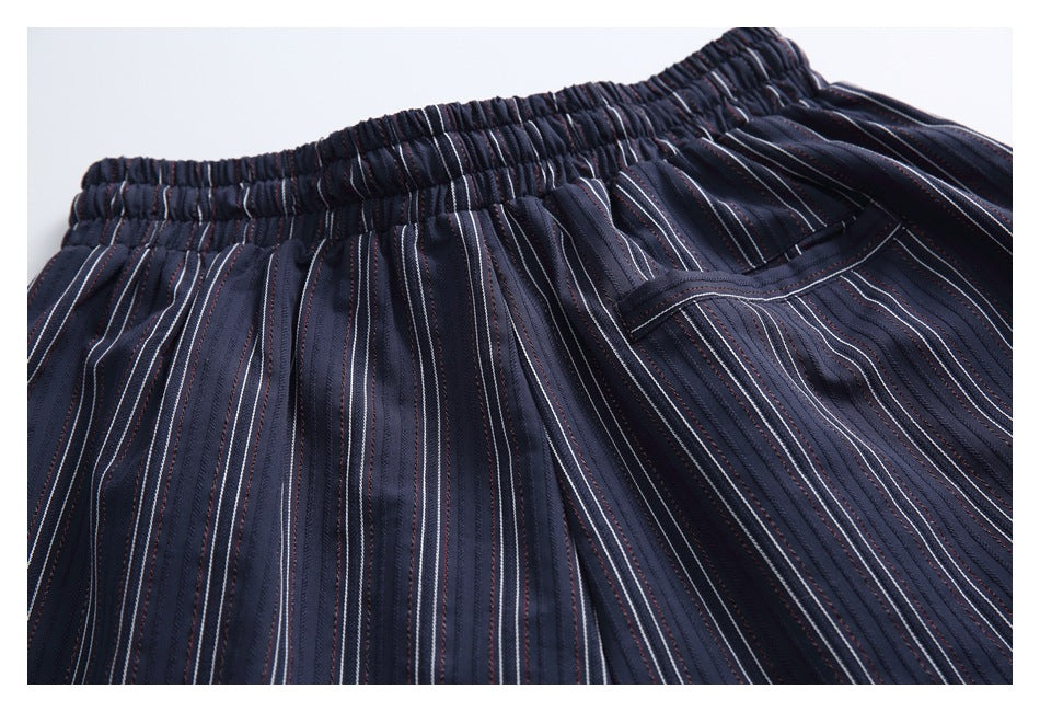 Close-up of dark navy striped trousers with an elastic waistband and a side pocket.