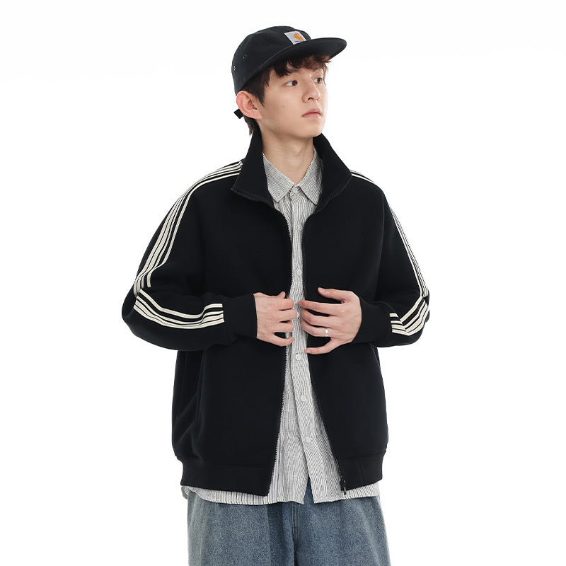 Model wearing a black zip-up track jacket with a stand collar and cream triple stripes down the sleeves.