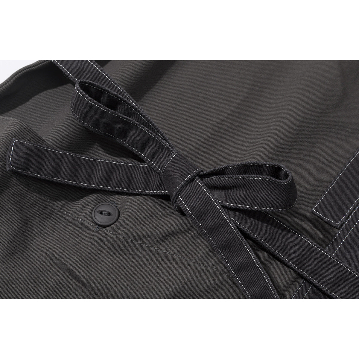 Close-up of a charcoal jacket's tied belt, button, and contrasting topstitching.