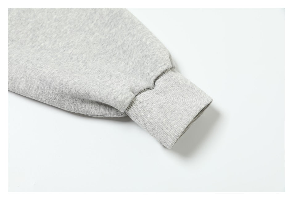 Close-up of a light heather gray sleeve ending in a ribbed cuff.