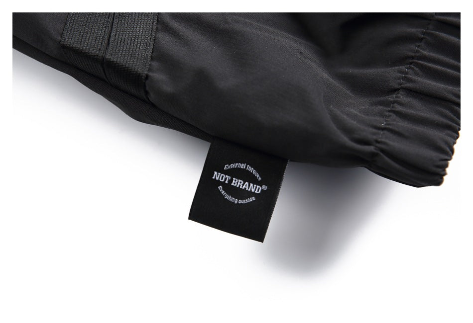 Close-up of a black garment's gathered edge and attached black label reading “NOT BRAND.”