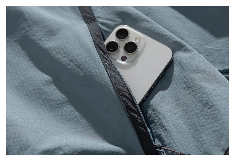 Close-up of a white smartphone tucked into a pocket in a blue-gray garment with dark trim.