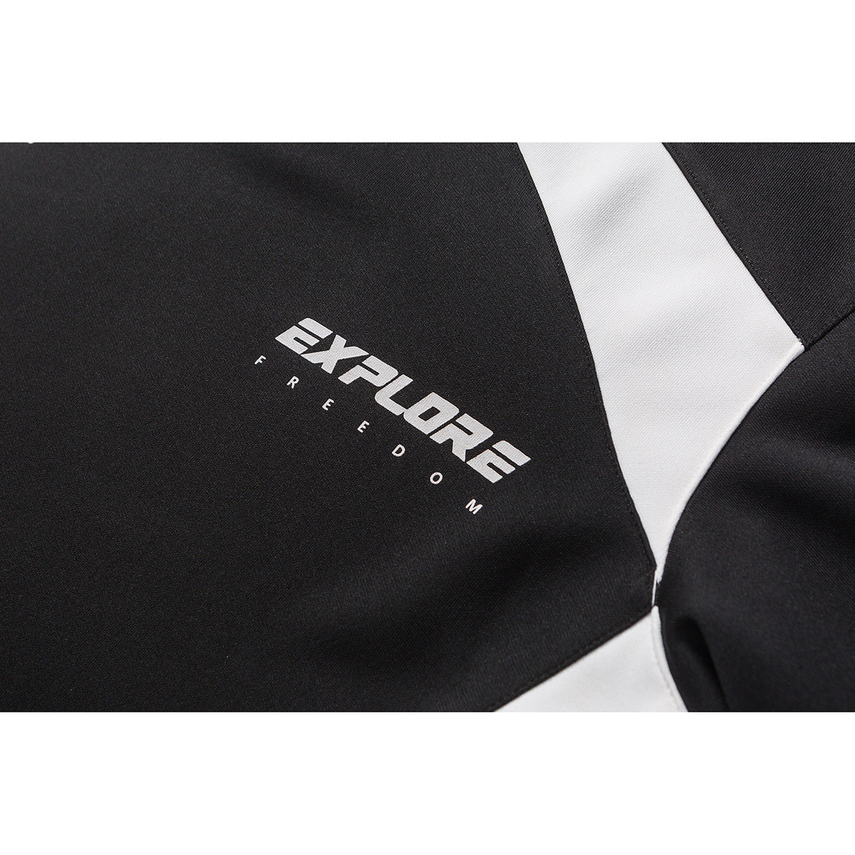 Close-up of white “EXPLORE FREEDOM” lettering printed on the black shirt beside a white panel.