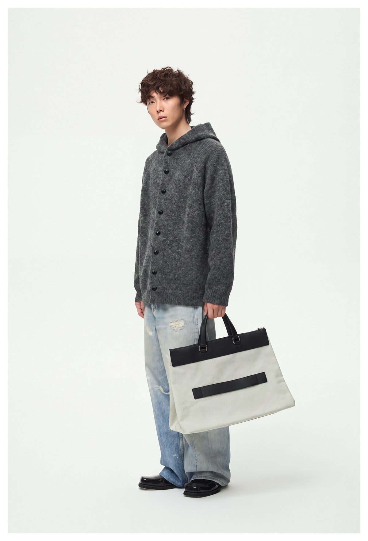 Full-length model wearing a charcoal gray button-front hooded cardigan with light blue jeans and carrying a large tote.