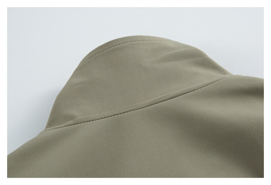Close-up of the raised collar and stitched seam on an olive-gray jacket.